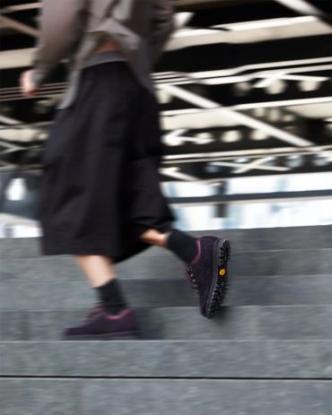 Person walking up stairs wearing black shoes and dark clothing.