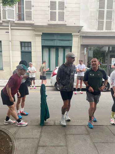Group of men in athletic wear preparing for a run on a city sidewalk.