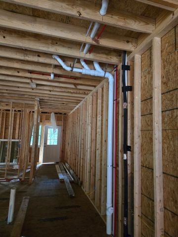 Interior framing and plumbing of a house under construction.