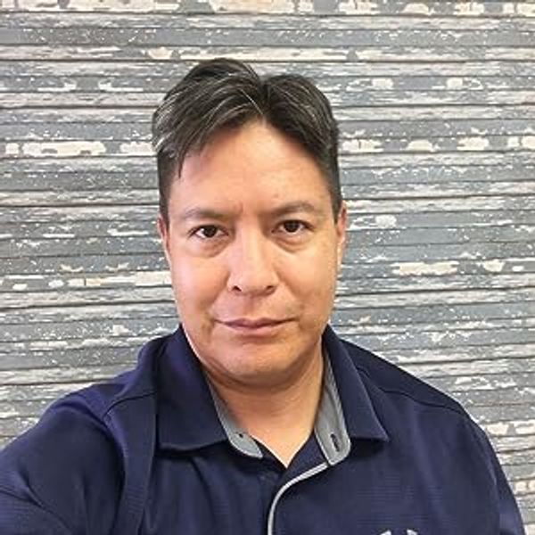 Man in a navy blue shirt against a textured gray wall.