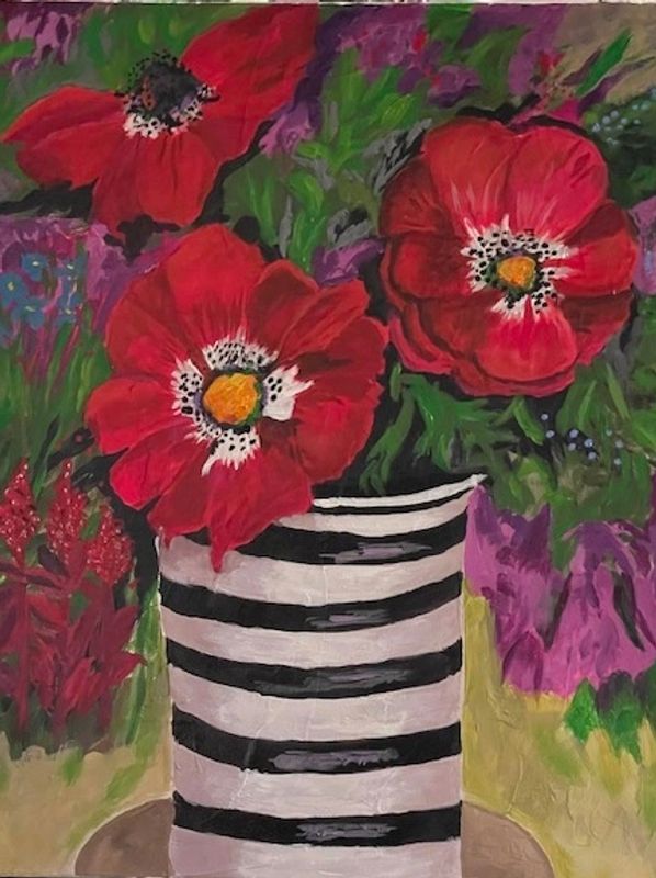Bright red flowers in a striped black and white vase.