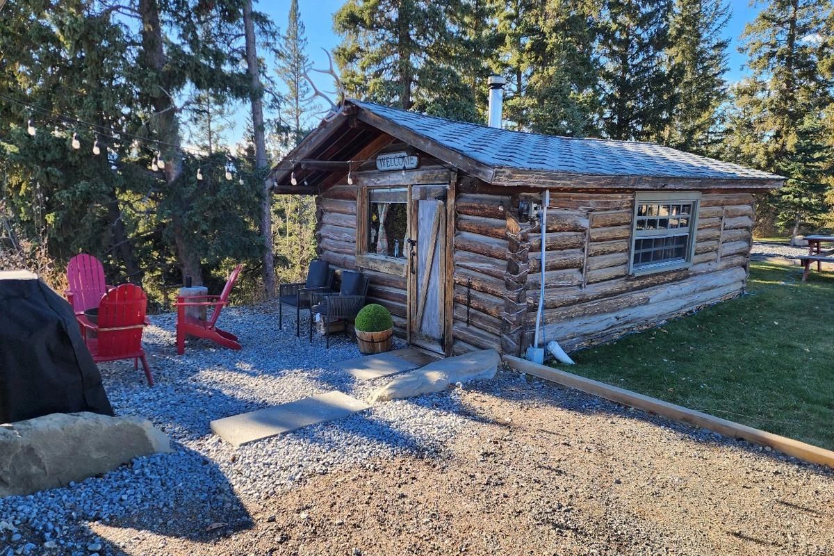100 year old log cabin with red oit door chairs