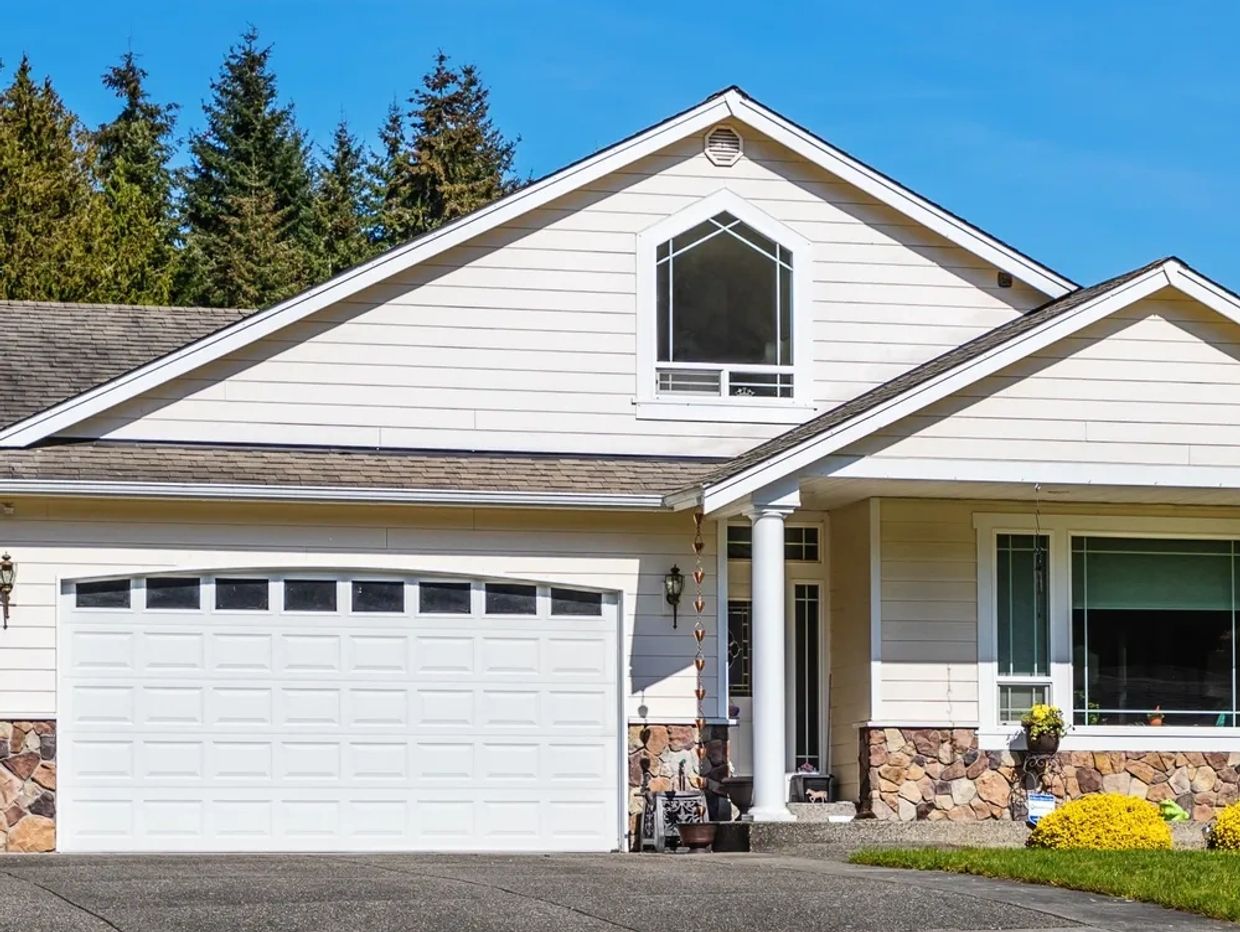 Modern house exterior with white garage door and stone accents.