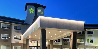 Exterior view of a well-lit extended stay hotel at dusk.