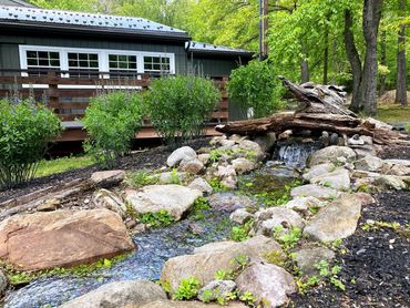 Flowing rock stream and landscaped garden beside a rustic lodge building at Whitetail Lodge.