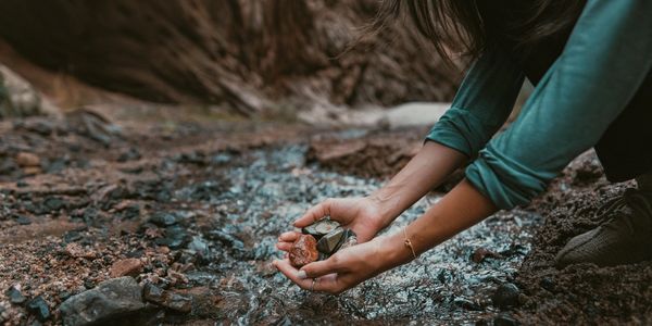 woman's hands holding rocks in a stream