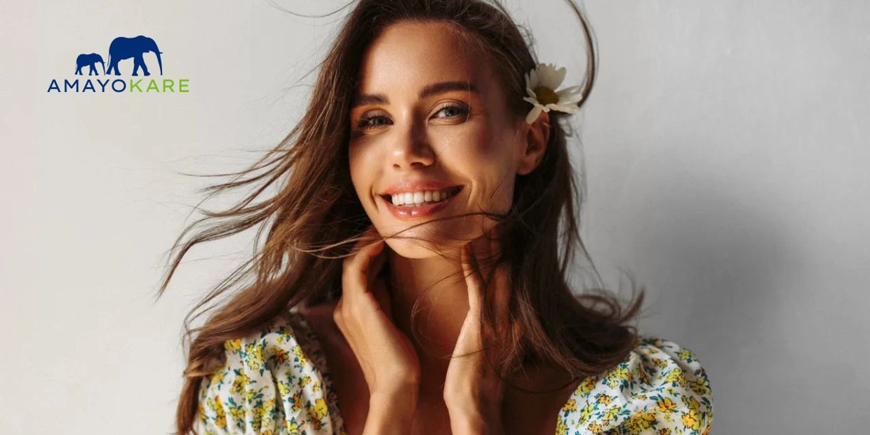 A woman with flowing hair and a flower smiles warmly in a floral dress.