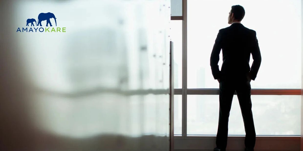 Man in a suit looking out a large window in an office.