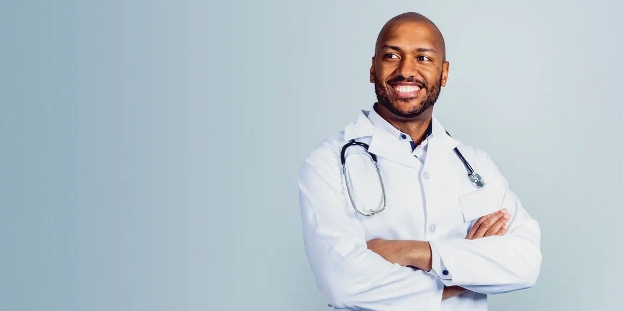 Smiling male doctor with crossed arms and stethoscope.