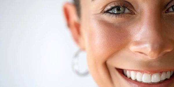 Close-up of a smiling woman with bright eyes and clear skin.