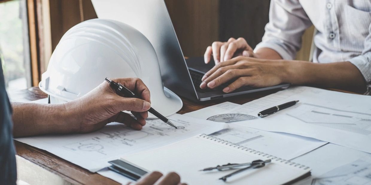 Two people working on architectural or engineering plans.