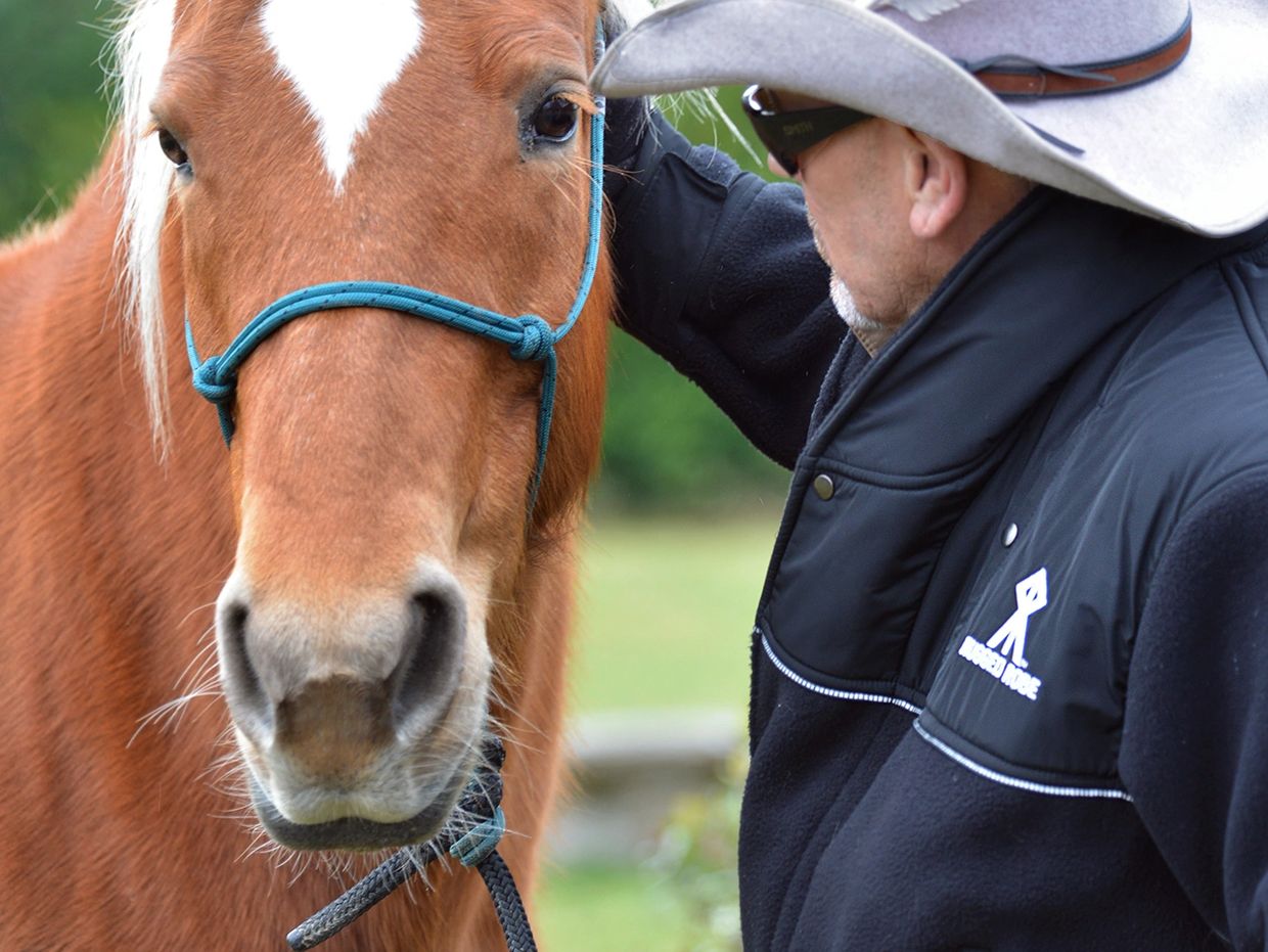 Man in a cowboy hat with a horse in a rugged robe