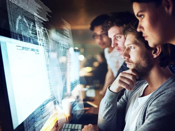 Team focused on digital data analysis at computer.