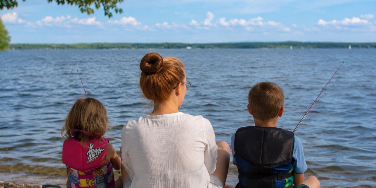 Woman and two kids fishing by the lake.