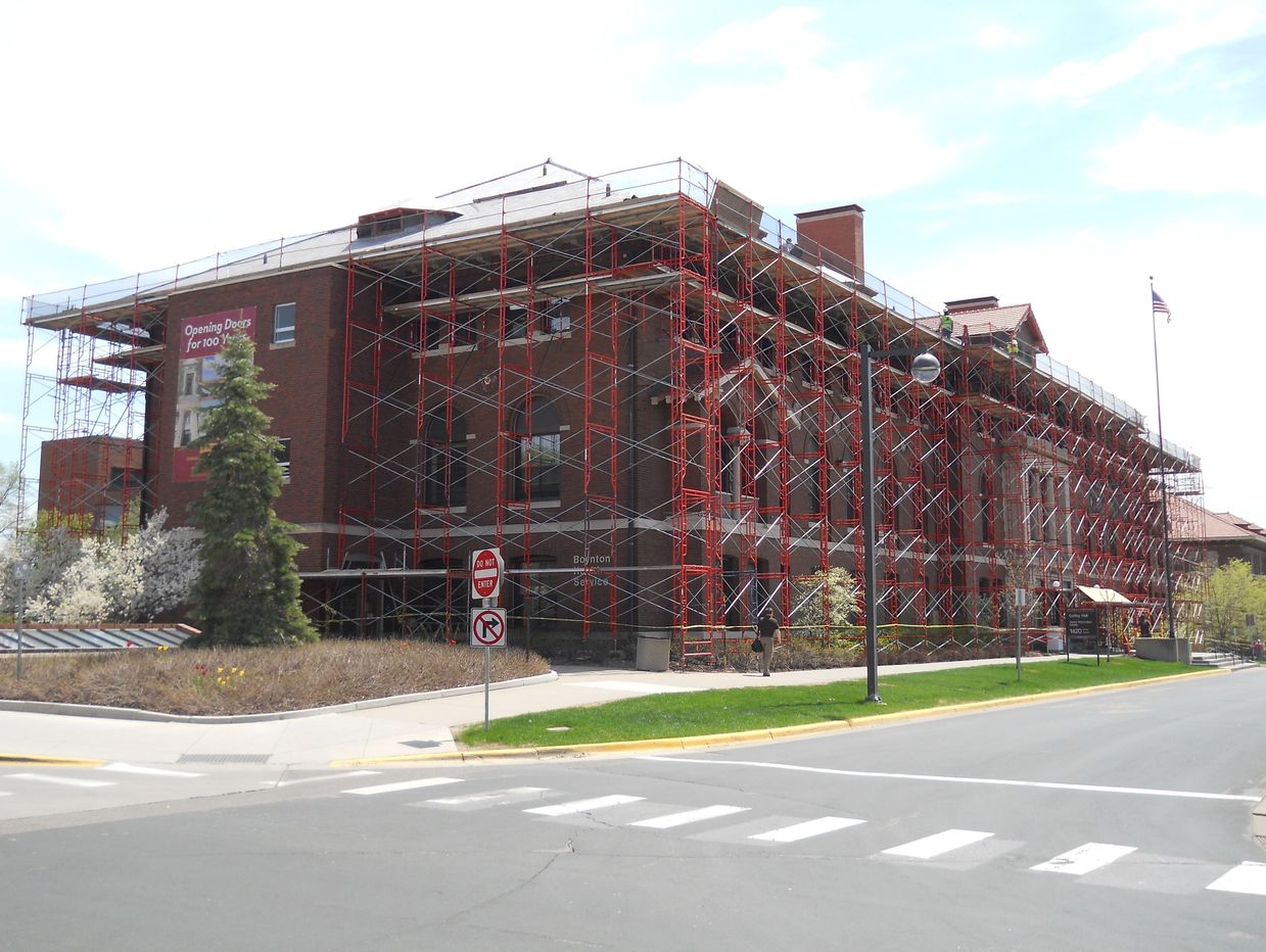 Large brick building under renovation with scaffolding covering its exterior.