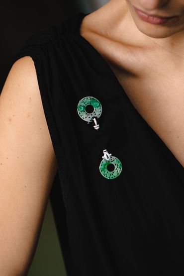 Close-up of green and black stone jewelry on black dress.