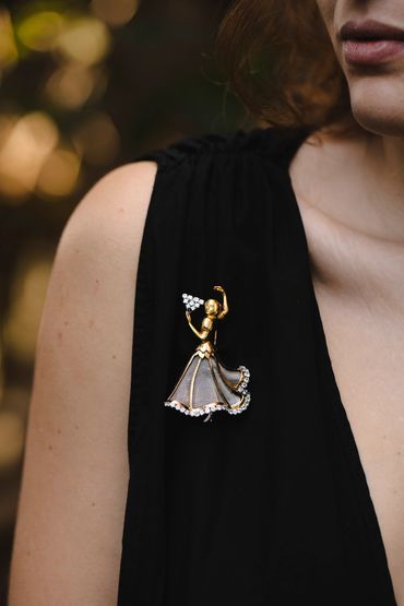Elegant brooch of a dancing woman on a black dress.