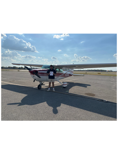 Man standing in front of small airplane holding a paper.