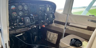 Cockpit view of a small airplane showing controls and headset.