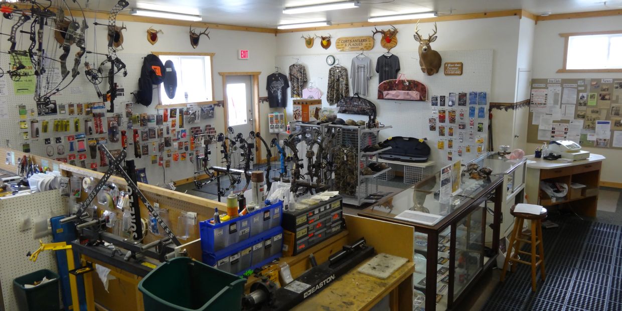 Interior of a hunting archery shop with bows, accessories, and mounted deer heads.