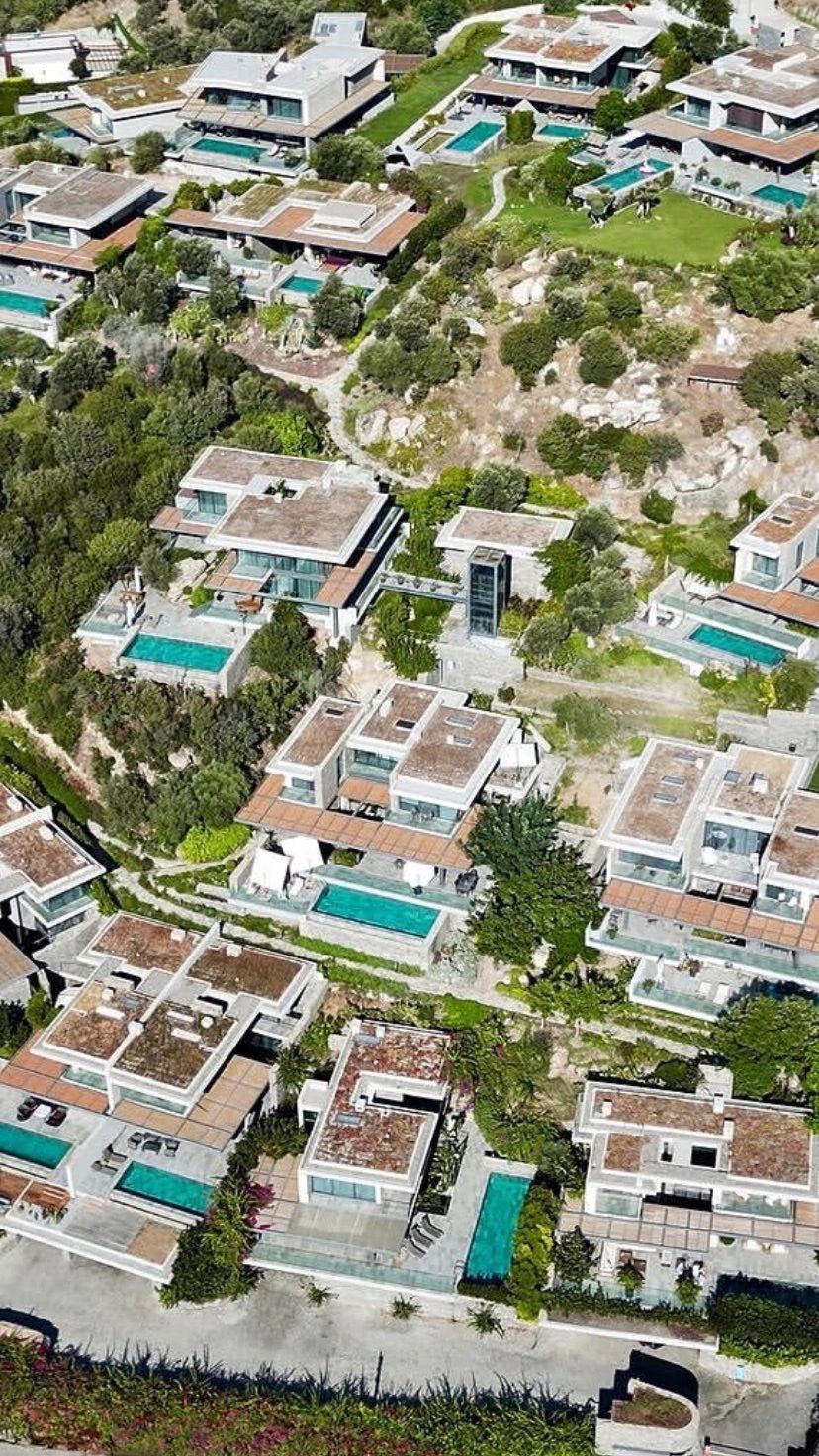 Aerial view of modern villas with private pools surrounded by greenery.