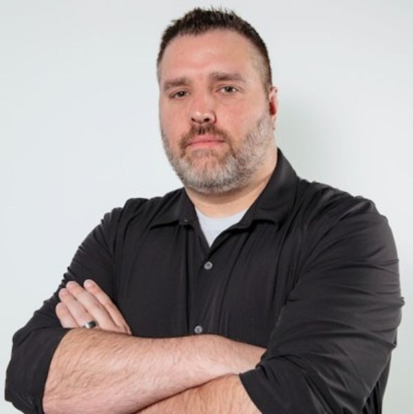 Confident man with arms crossed wearing a black shirt.