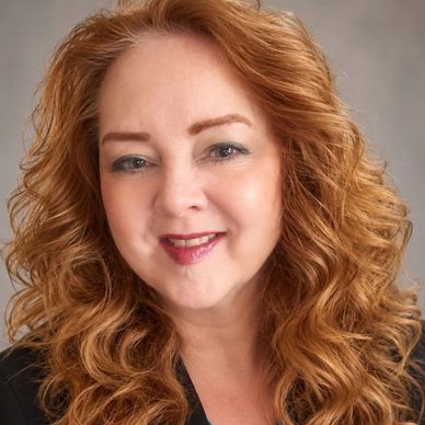 Smiling woman with curly red hair.