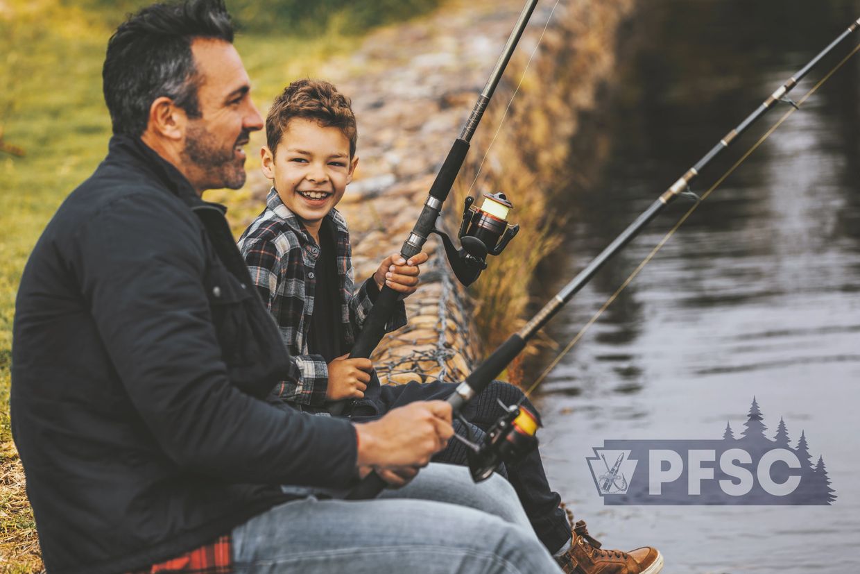 A father and son fishing happily by the water's edge.