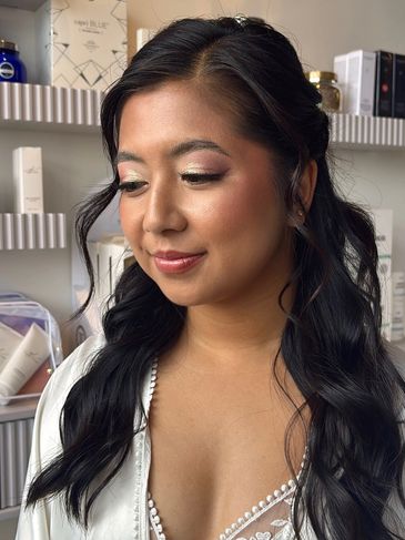 Young woman with elegant makeup and wavy black hair smiles softly.