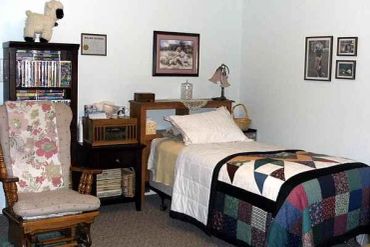 Cozy bedroom with floral chair and patchwork quilt.