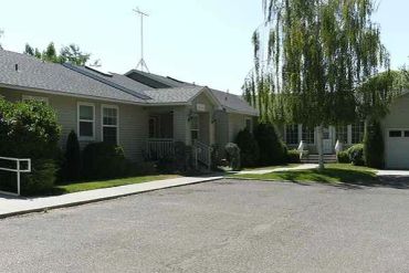 A small house with greenery and a paved driveway.