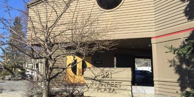 Building entrance with a sign reading '821 4th Street Plaza' and leafless tree nearby.