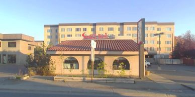 Small restaurant building with a hotel in the background.