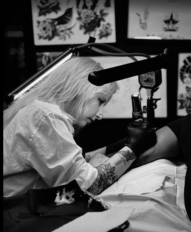 Tattoo artist working on a client's arm in a studio.