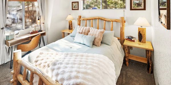 Cozy rustic bedroom with wooden furniture and soft bedding.