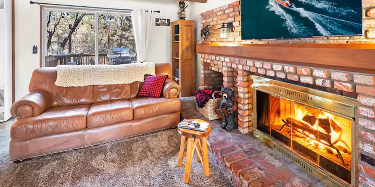 Cozy living room with a leather sofa and a roaring fireplace.