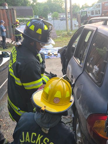 Firefighters in gear at a car accident scene.