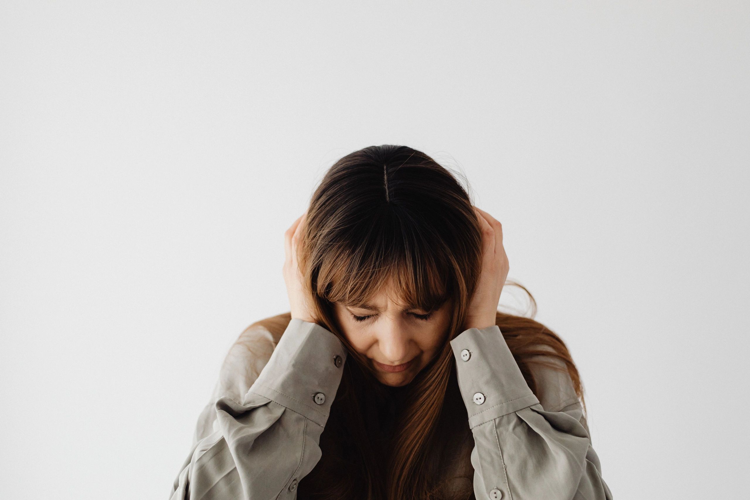 Woman covering her ears in discomfort from tinnitus (ringing in the ears)