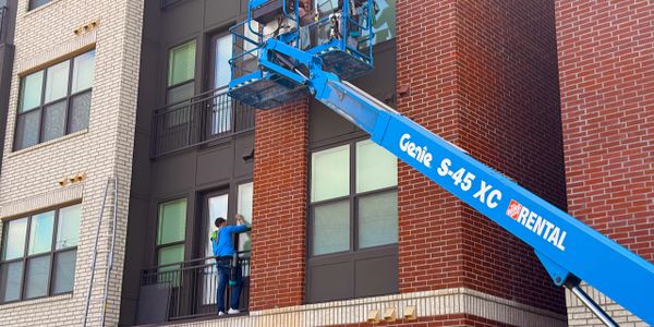 Workers use a Genie S-45 XC lift for building maintenance.