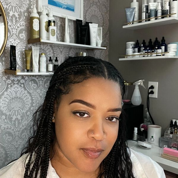 Woman with braided hair posing in a skincare or beauty product room.