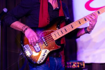 Musician playing an electric bass guitar with vibrant stage lighting.