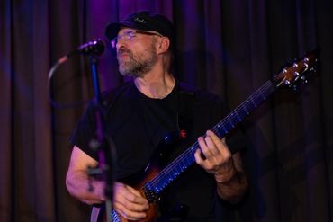 A man playing an electric guitar on stage with a microphone in front.