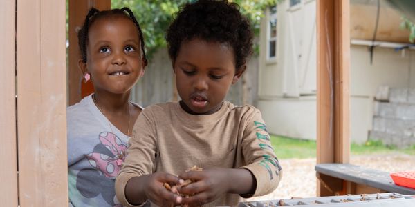 Two children playing and exploring outdoors with curiosity.