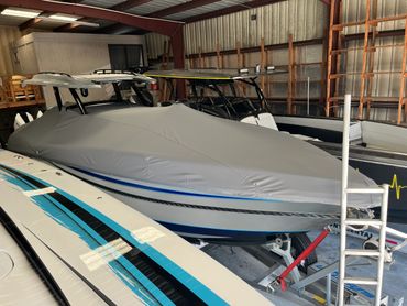 Boat covered with a protective gray tarp inside a storage facility.