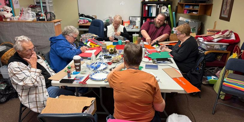 Group of elderly people crafting together at a table indoors.