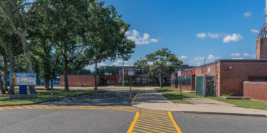 Exterior view of a school building with trees and a clear sky.