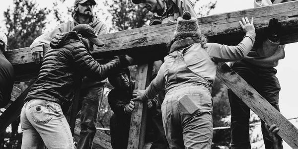 A group of people working together to lift a wooden structure outdoors.