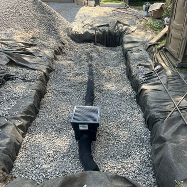 Drainage system installation with gravel and protective fabric.