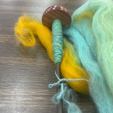 Drop spindle with yellow and aqua fiber