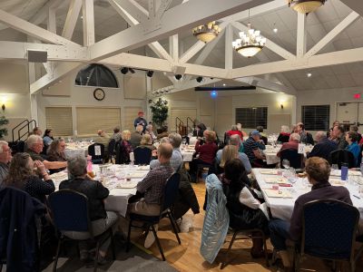 People seated at round tables in a banquet hall.